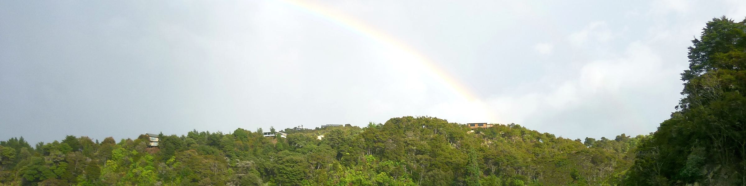 A rainbow arcing over the bush-clad headland above Kaiteriteri