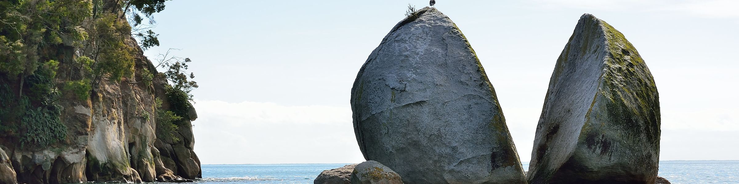 The cleft granite boulder of Split Apple Rock standing in calm sea