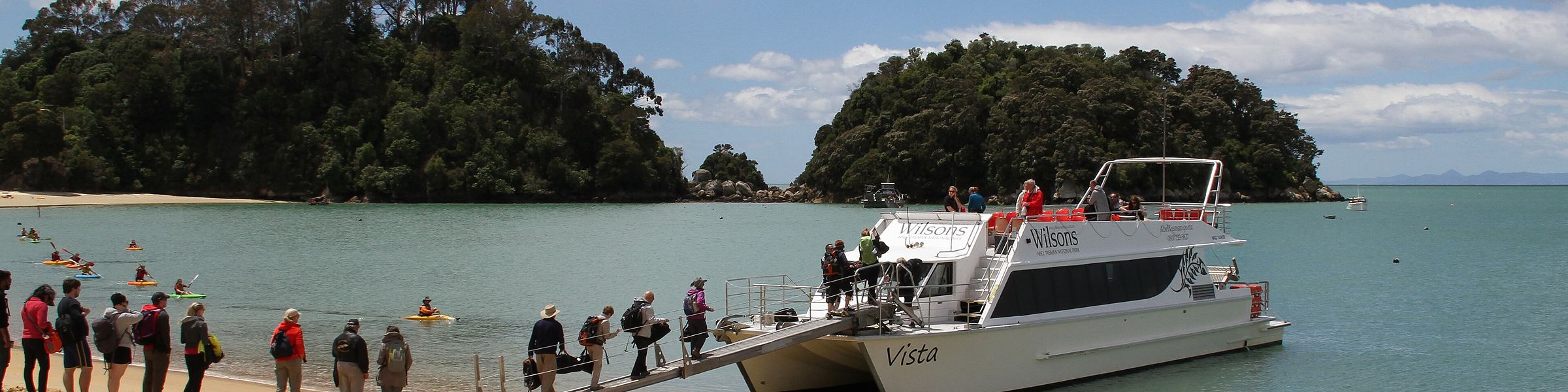 A launch at the shoreline at Kaiteriteri with day-trippers boarding