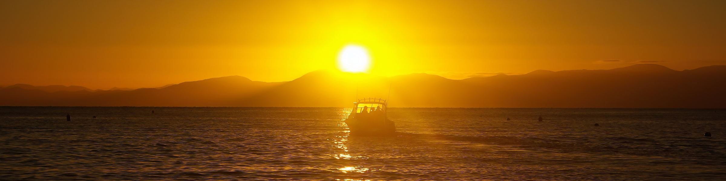 Sunrise over the water at Kaiteriteri with a boat silhouetted